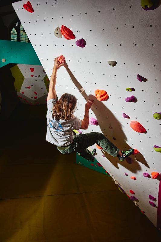 Image of a climber bouldering on a steep indoor boulder problem